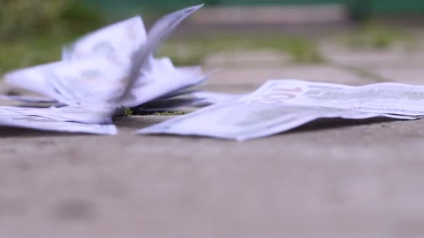 Money fly across the sidewalk from the wind close up — Stock Video