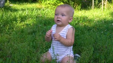 küçük bebek otların arasında oturan ve hd gülümseyen