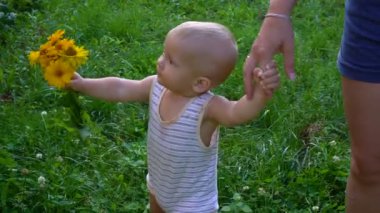 erkek bebek sarı çiçekler ile yürüyor