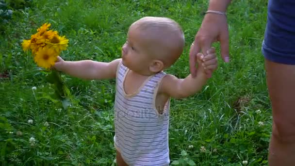 O menino está andando com flores amarelas — Vídeo de Stock