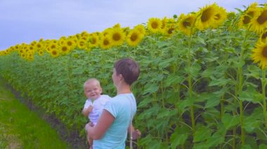 Anne ve oğlu ayçiçeği bir çiçek ile oynamak