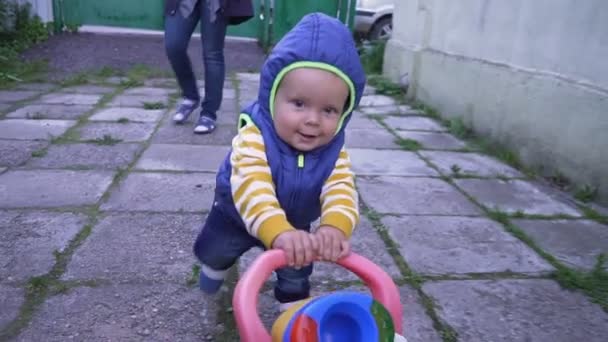 Ребенок на улице ходит с игрушкой смешно — стоковое видео