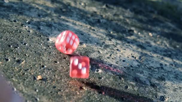 Red dice rolling on a concrete slab in slow motion — Stock Video