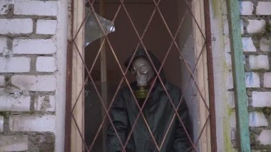 Bir gaz maskesi olan bir adam penceresinden çubuklarıyla görünüyor ve ücretsiz devam edemez