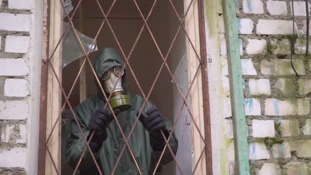Ein Mann mit Gasmaske schaut aus einem Fenster mit Gittern und kann sich nicht befreien — Stockvideo