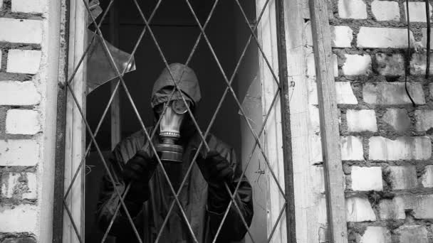 Um homem com uma máscara de gás olha da janela com barras e não pode ir livre — Vídeo de Stock