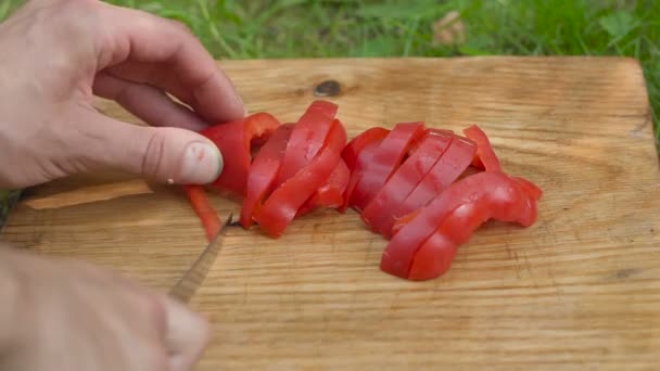 Hombre rebanadas pimiento rojo con un cuchillo de cerca — Vídeo de stock