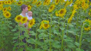 Anne ve oğlu ayçiçeği bir çiçek ile oynamak