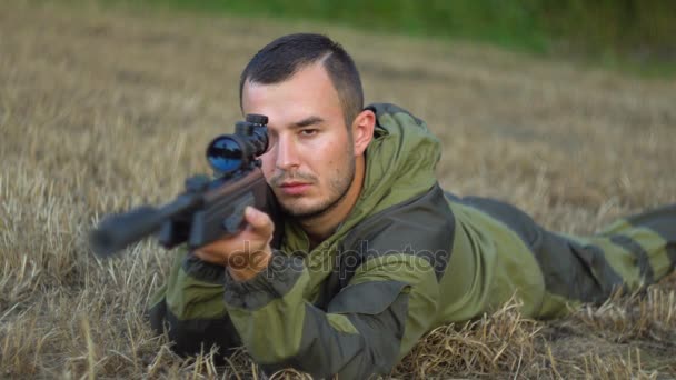 Hombre en camuflaje con un arma yace en el suelo — Vídeos de Stock