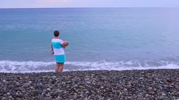 Mutter mit Baby spaziert am Strand entlang 4k — Stockvideo