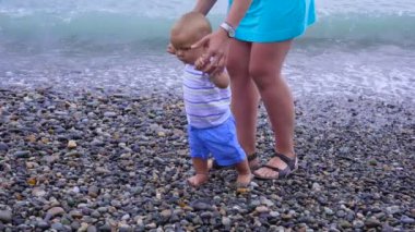 Anne küçük bir çocukla plaj boyunca yürür