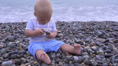 küçük çocuk bir kumsalda oturuyor