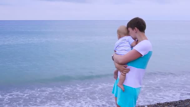 Мама з дитиною гуляє уздовж пляжу — стокове відео