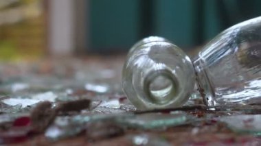 bir bardak votka kırık cam arka plan üzerinde. düşmüş bir şişe