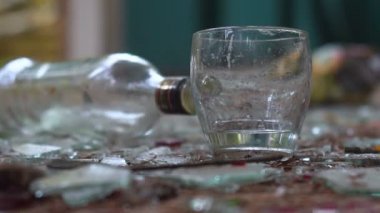 bir bardak votka kırık cam arka plan üzerinde. düşmüş bir şişe