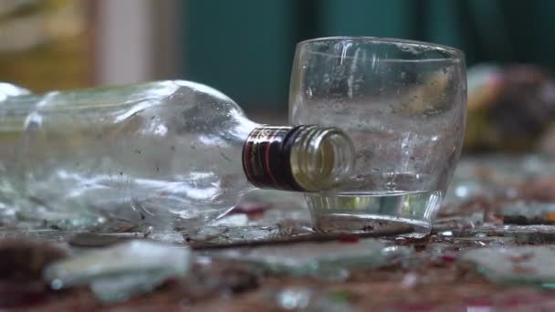 Un bicchiere di vodka sullo sfondo di vetro rotto. una bottiglia caduta — Video Stock