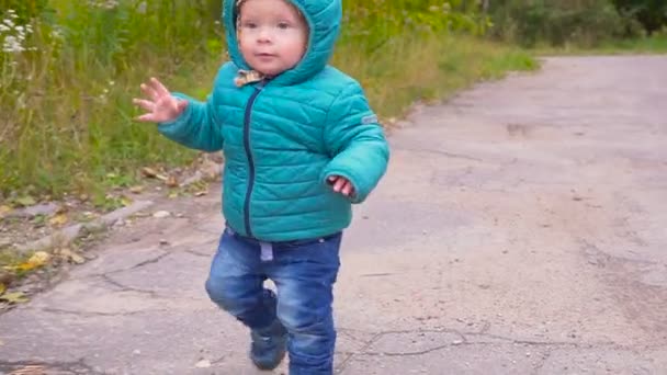 Ein ohrenbetäubender Junge läuft durch den herbstlichen Park und lächelt in Zeitlupe. Gimbal — Stockvideo
