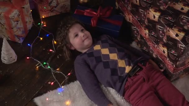 Flickan ligger nära julgran, utseende och leenden — Stockvideo