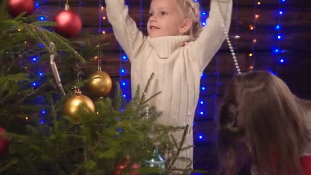 Duas meninas decorar uma árvore de Natal e conversar — Vídeo de Stock