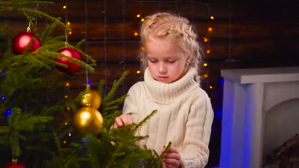 Menina veste-se uma árvore de Natal — Vídeo de Stock