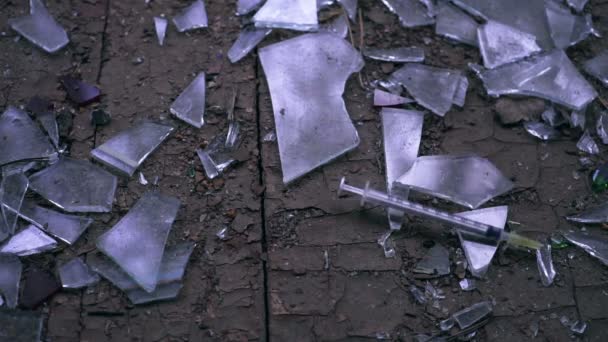 Jeringa cayendo rociando sangre después de una inyección de cocaína de heroína en cristales rotos . — Vídeos de Stock