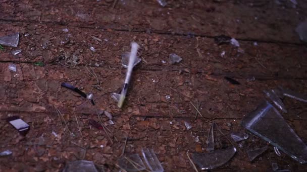 Syringe falling down spraying blood after a heroin cocaine injection on broken glass. — Stock Video