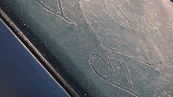 Corazón símbolo de amor en vidrio congelado ventana del coche cubierto de nieve — Vídeo de stock