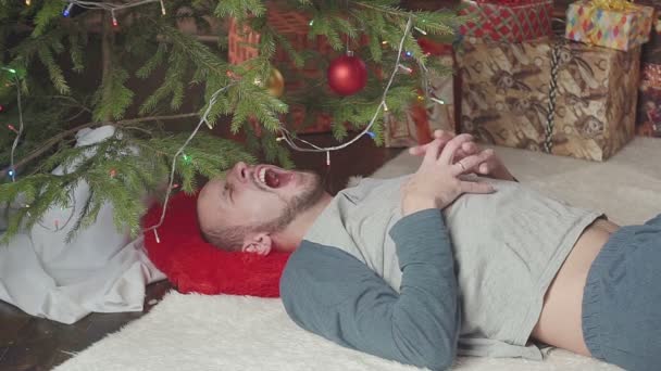 Giovane assonnato vicino all'albero di Natale — Video Stock