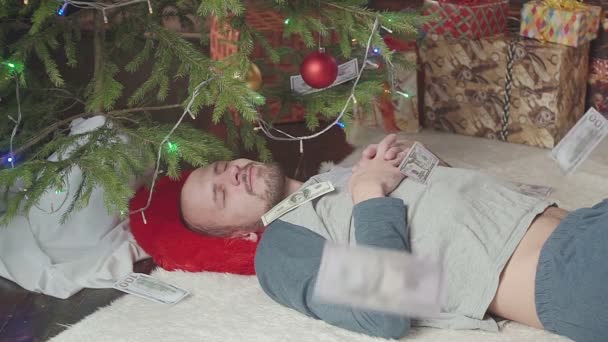 Chute de dollars. Un homme dort près d'un arbre de Noël — Video