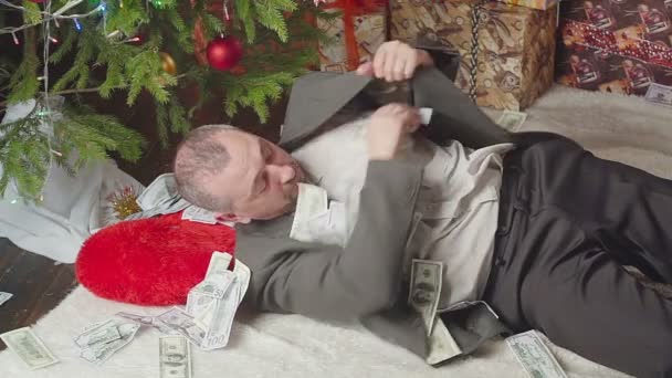 Un uomo va a letto con un sacco di dollari e un albero di Natale — Video Stock