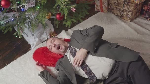 A man is sleeping with a lot of dollars and a Christmas tree — Stock Video