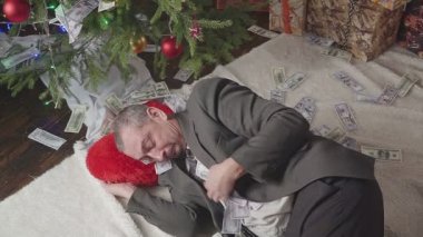 Bir adam bir sürü dolar ve bir Noel ağacı ile uyuyor