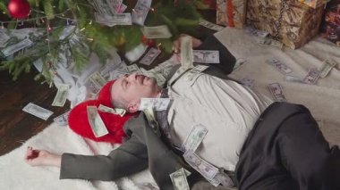 Bir adam bir sürü dolar ve bir Noel ağacı ile uyuyor