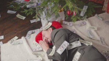Bir adam bir sürü dolar ve bir Noel ağacı ile uyuyor
