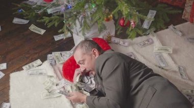 Bir adam bir sürü dolar ve bir Noel ağacı ile uyuyor
