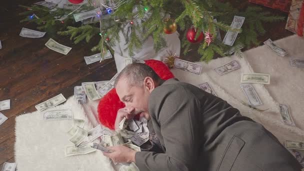 Ein Mann schläft mit vielen Dollars und einem Weihnachtsbaum — Stockvideo