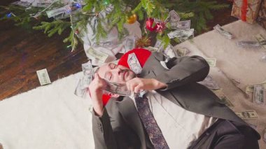 Bir adam bir sürü dolar ve bir Noel ağacı ile uyuyor