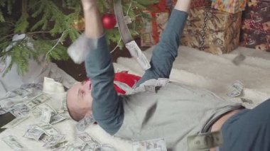 Bir adam bir sürü dolar ve bir Noel ağacı ile uyuyor