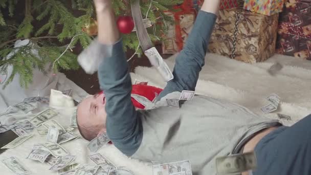 En man sover med en massa dollar och en julgran — Stockvideo