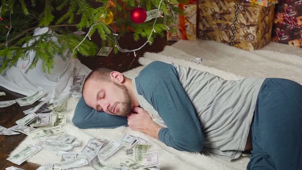 En man sover med en massa dollar och en julgran — Stockvideo