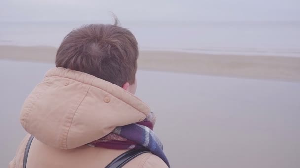 La fille se tient au bord de la mer et regarde au loin — Video