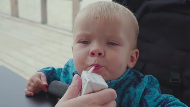 A child drinks from a straw juice closeup — Stock Video