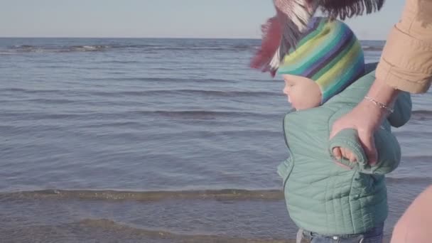 Maman avec un petit enfant marche le long de la plage de printemps — Video