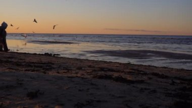 Mutlu bir aile deniz kıyısında yürüyüş. Siluetleri günbatımı.