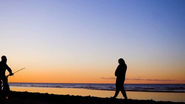 幸せな家族は海岸の上を歩きます。シルエットの夕日. — ストック動画