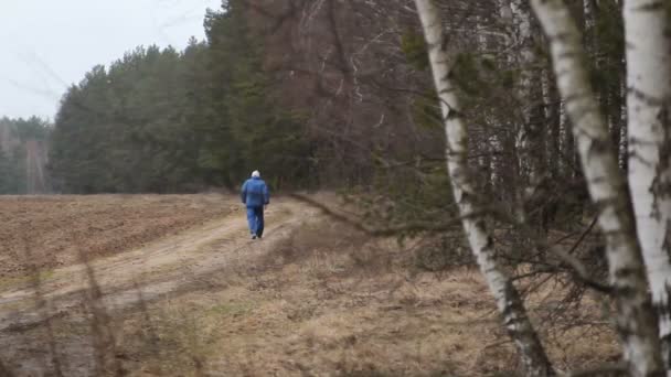 Un uomo che cammina su una pista forestale in primavera — Video Stock