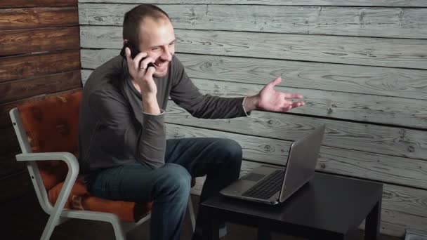 Jovem freelancer caucasiano fala ao telefone e fala sobre sucesso — Vídeo de Stock
