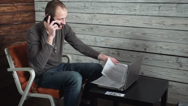 Jovem freelancer caucasiano fala ao telefone e fala sobre sucesso — Vídeo de Stock