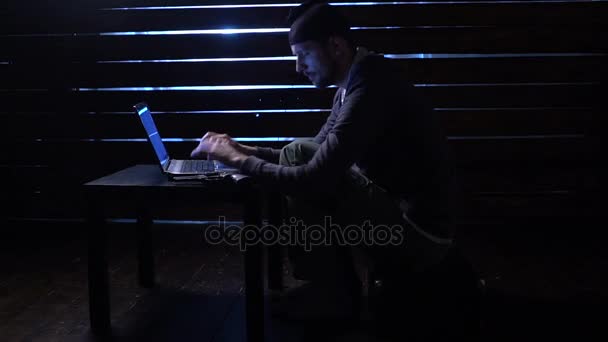 Смешной хакер совершает кибератаку с ноутбуком и пистолетом в руках — стоковое видео