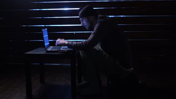 Комічний смішний хакер здійснює кібератаку з ноутбуком і пістолетом в руках — стокове відео